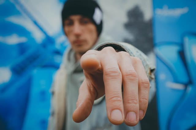 VEYNE mit ausgestreckter Hand vor einer blauen Wand