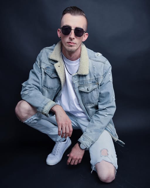 VEYNE mit Sonnenbrille und Jeansjacke vor dunklem Hintergrund